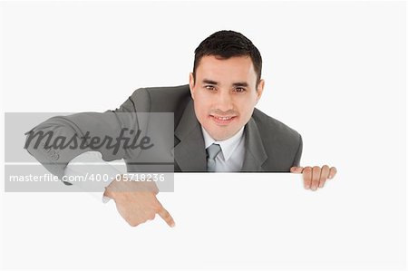 Businessman pointing at sign under him against a white background