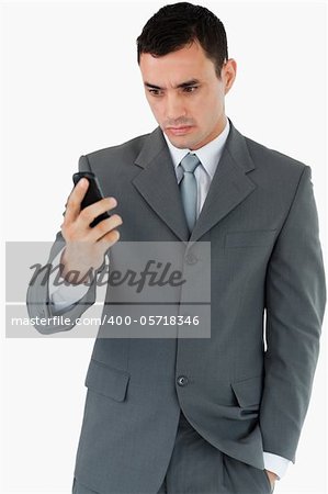 Serious looking businessman looking at his cellphone against a white background