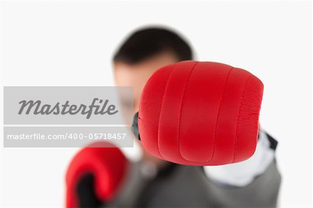 Close up of boxing glove being used to slam by businessman against a white background