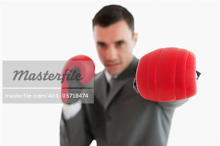 Close up of boxing glove being used by businessman against a white background