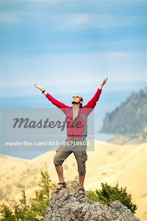 Man on top of mountain holding arms up