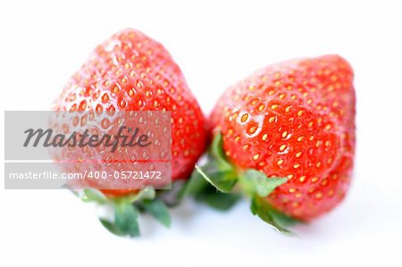 Two red strawberry fruits on a white background