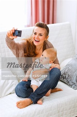 Beautiful young mom making photos with her lovely baby at home
