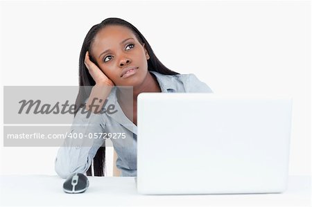 Businesswoman day dreaming while using a laptop against a white background