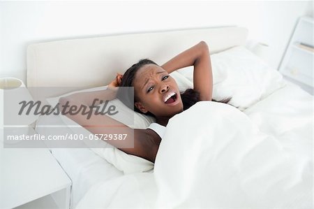 Woman yawning on her bed while looking at the camera