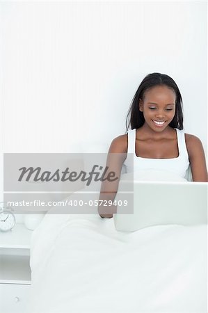 Portrait of a smiling woman using a notebook before sleeping in her bedroom