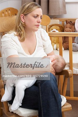 Worried Mother Breastfeeding Baby In Nursery
