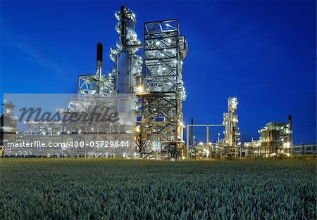 Refinery at night with a cornfield in the foreground