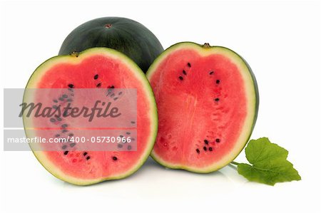 Watermelon fruit sliced in half with leaf sprig isolated over white background.