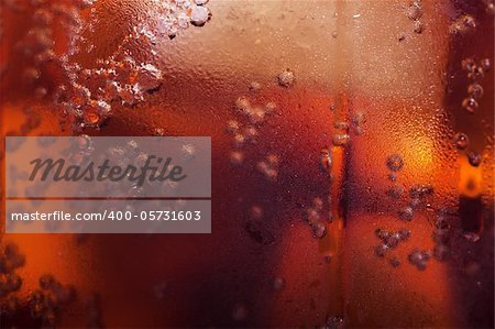 Macro view of cold cola in a glass with ice cubes