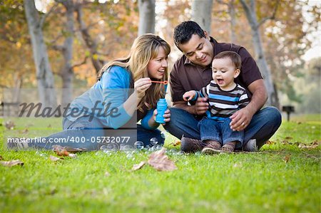 Happy Young Mixed Race Ethnic Family Playing with Bubbles In The Park.