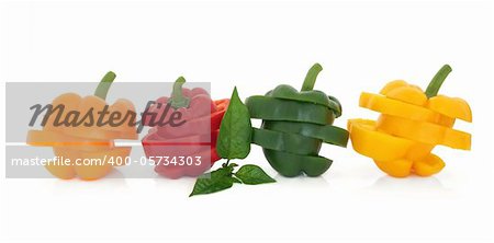 Orange, red, green and yellow sliced pepper vegetables in layered stacks with leaf sprig isolated over white background.