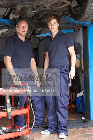 Mechanic and apprentice working on car