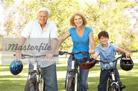 Grandparents And Grandson On Cycle Ride In Park