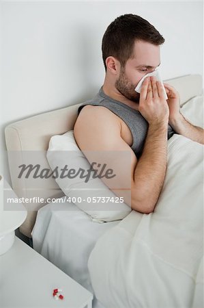 Portrait of a man blowing his nose in his bedroom