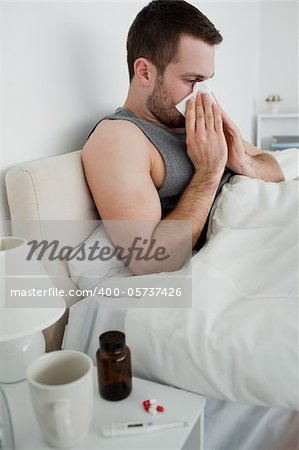 Portrait of a sick man blowing his nose in his bedroom