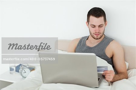 Attractive man shopping online in his bedroom