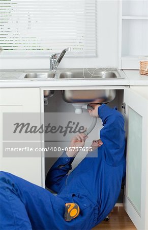 Portrait of a repairman fixing a sink in a kitchen