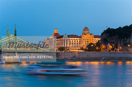 Budapest night view. Long exposure with boat silhouette on river. Hungarian landmarks, Freedom Bridge and Gellert Hotel Palace.