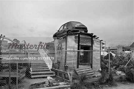 Rusty car and scrap metal at a junkyard. Black and white.