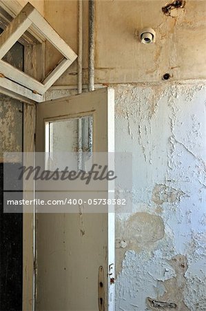 Door frame and peeling paint wall in abandoned house interior.