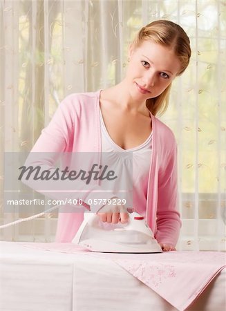 Happy young beautiful woman ironing clean clothes