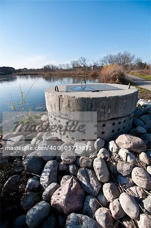 A perforated concrete pipe forms part of a stormwater management system in a suburban pond.