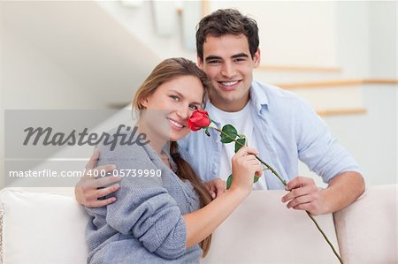 Young man offering a rose to his girlfriend in their living room