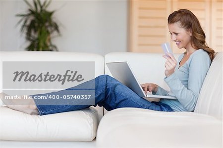 Young woman booking flight online on her sofa