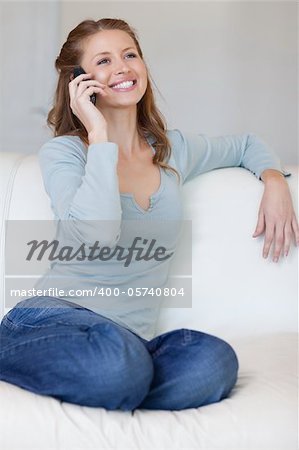 Smiling young woman on the sofa answering the phone
