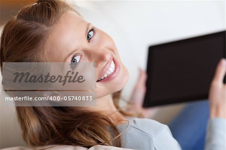 Shadowing smiling young woman on the sofa with tablet