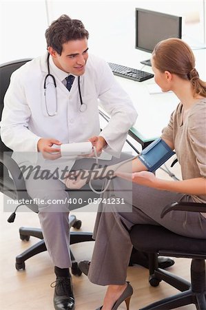 Side view of young doctor talking to his patient about blood pressure