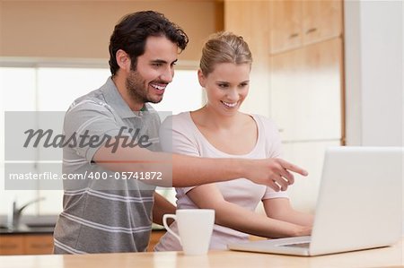 Couple using a notebook while having coffee in their kitchen