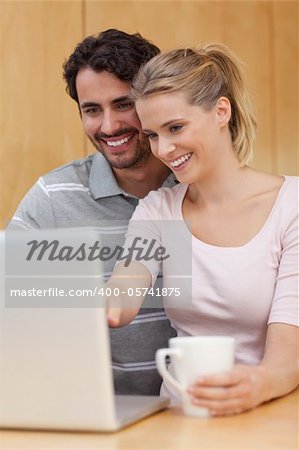 Portrait of a couple using a notebook while having tea in their kitchen