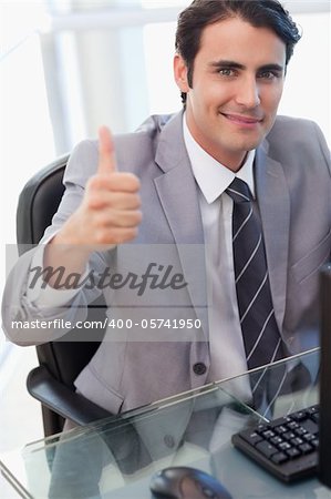 Portrait of a businessman working with a computer with the thumb up in his office