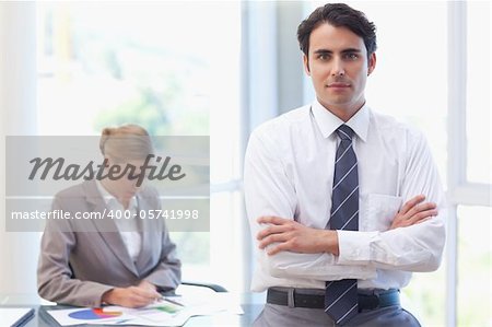 Businessman posing while his colleague is working in a meeting room