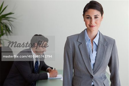 Beautiful businesswoman posing while her colleague is working in an office