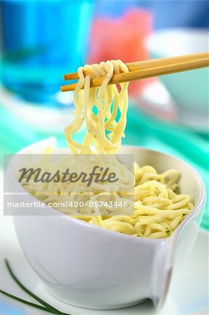 Vegetarian Asian noodle soup and some noodles on chopsticks (Selective Focus, Focus on the front chopstick and the noodles on it)