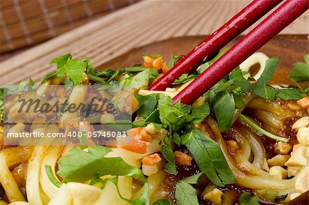 Close-up photograph of red chopsticks on freshly prepared Asian noodles.
