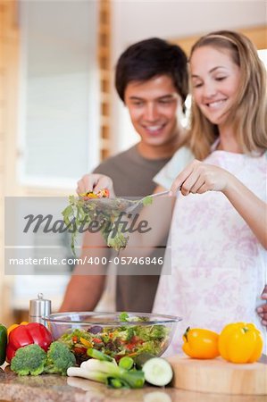 Portrait of a young couple making a salad in their kitchen