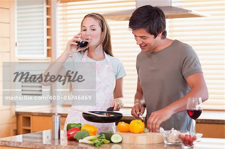 Couple cooking dinner while drinking wine in their kitchen