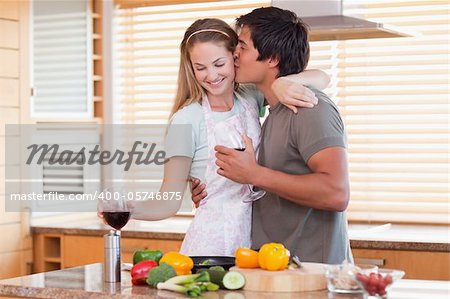 Lovely couple drinking red wine while kissing in their kitchen