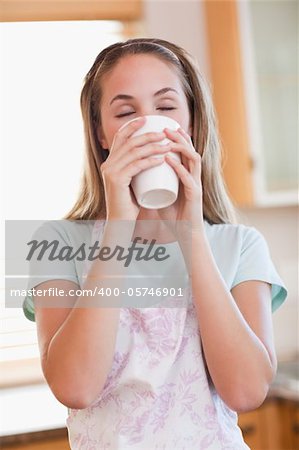 Portrait of a calm woman drinking a cup of tea in her kitchen