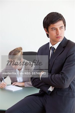 Portrait of a manager posing while his colleague is working in an office