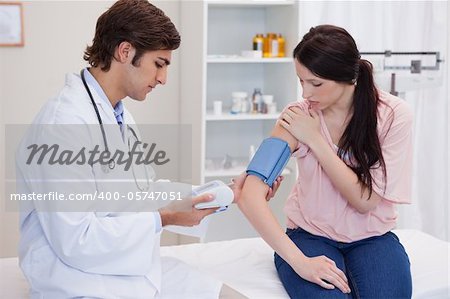 Young doctor taking patients blood pressure