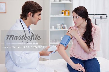 Young doctor checking patients blood pressure