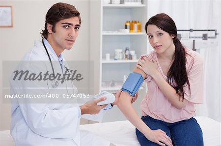 Doctor taking young female patients blood pressure