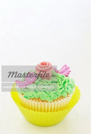 Vanilla cupcakes with buttercream icing and rose decorations on white background