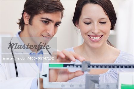 Young doctor and patient adjusting the scale together