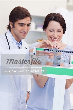 Young male doctor adjusting scale for his patient
